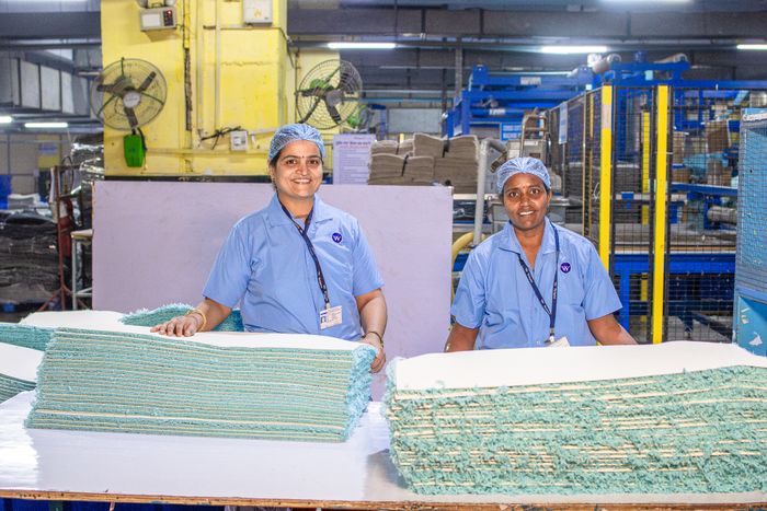 Two factory workers in blue uniforms working at a production line in India